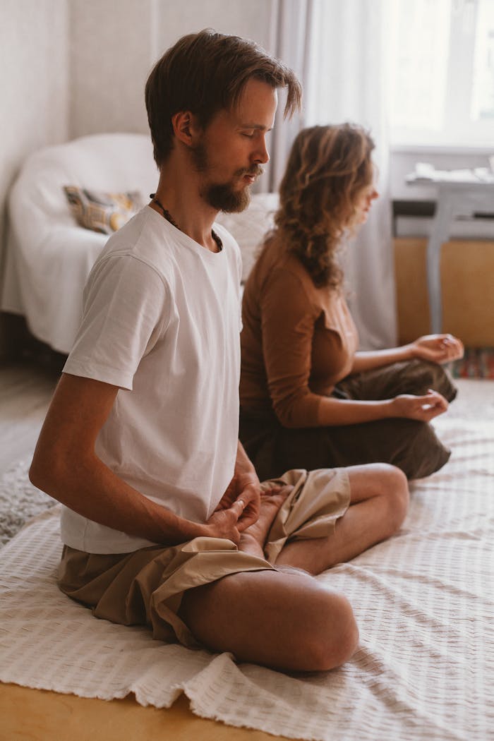 A man and woman meditating indoors, capturing tranquility and mindfulness.