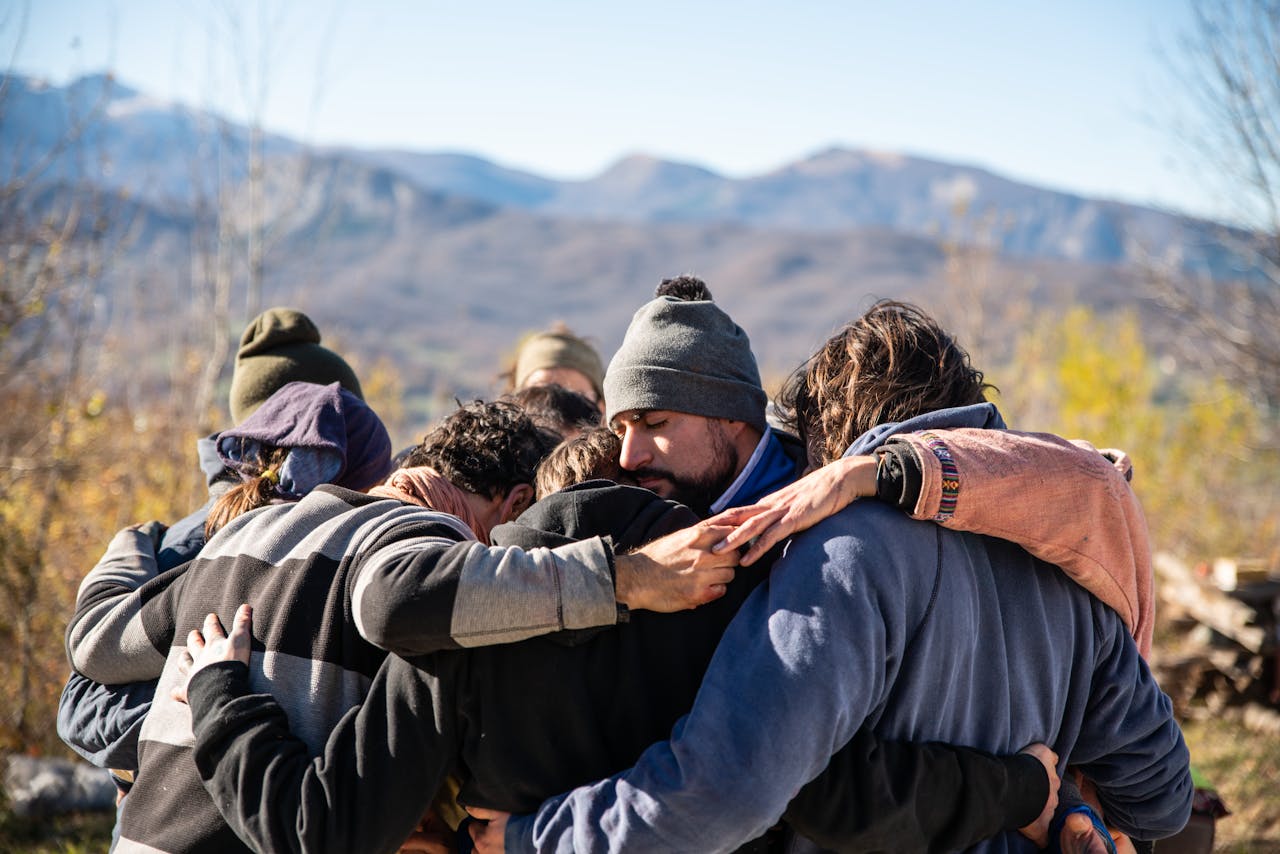 gallery-5 A group of friends embrace in a warm hug outdoors with a scenic mountain view.